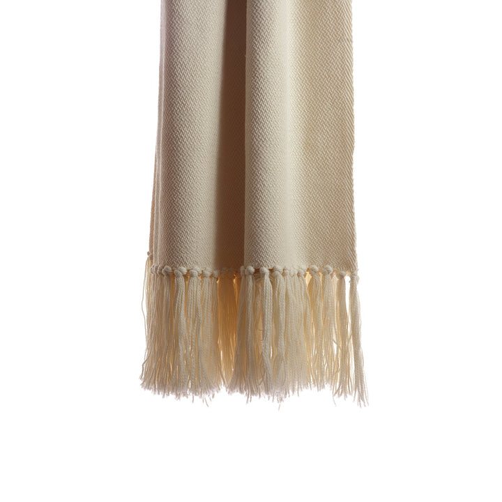 Hand-knotted fringe along the end of an ivory handwoven wool throw.