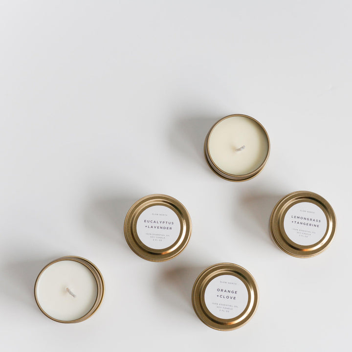 Mini 2 oz essential oil soy candle in a brushed gold travel tin with a lit cotton wick.