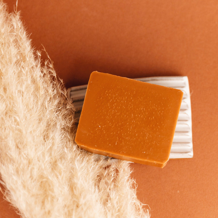 Bar soap with cinnamon and patchouli scent shown on a wooden surface.