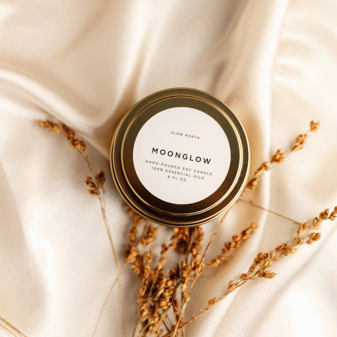 Moonglow travel tin candle with patchouli and cinnamon in a metal container.