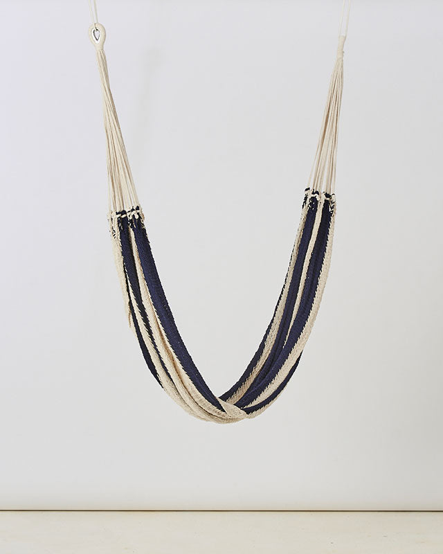 White and navy macrame mountaineer hammock with a woven design and hanging ropes.