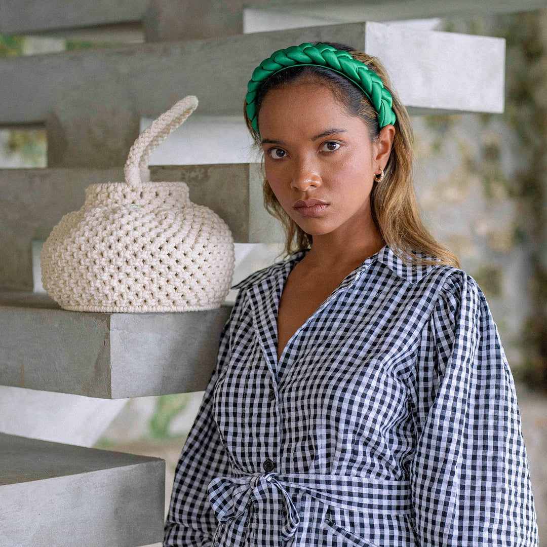 Off-white macrame bucket bag with a woven design and drawstring closure, a stylish boho accessory.