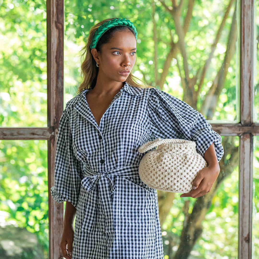 Off-white macrame bucket bag with a woven design and drawstring closure, featuring a bohemian style.