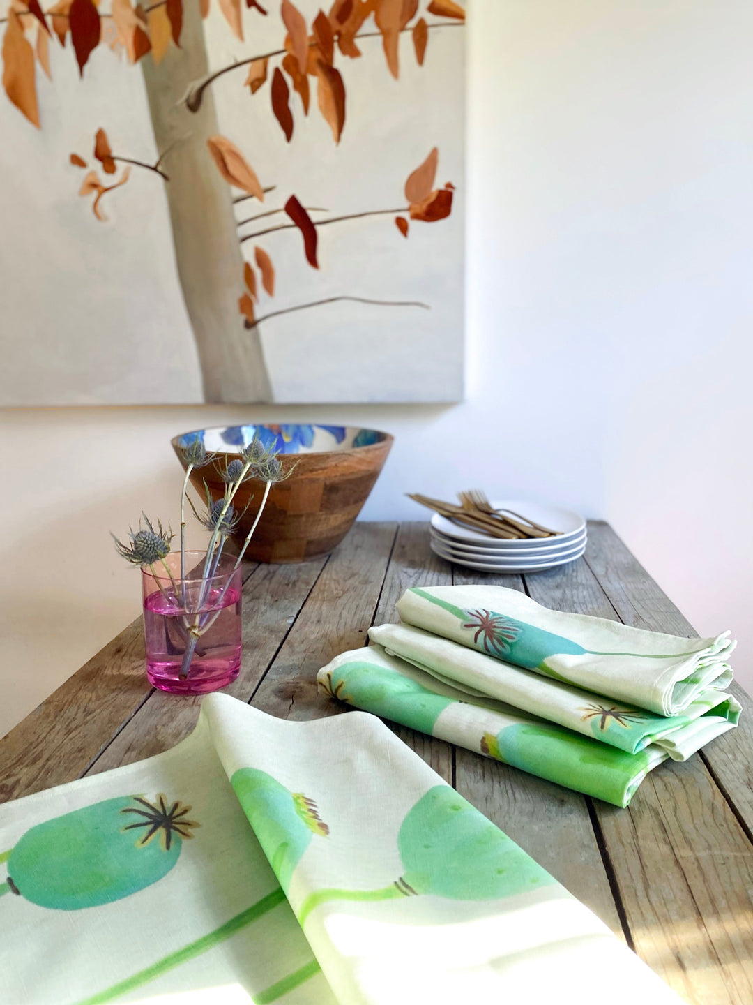 Set of four poppy pod napkins in heavyweight linen-cotton, arranged on a wooden table.