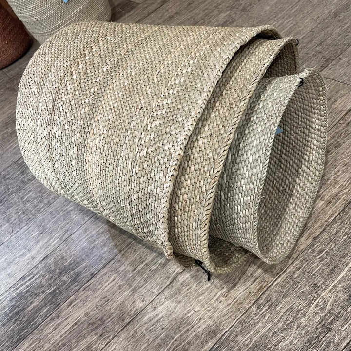 Three natural grass baskets nested inside one another, telescoped so all three rims stack into view