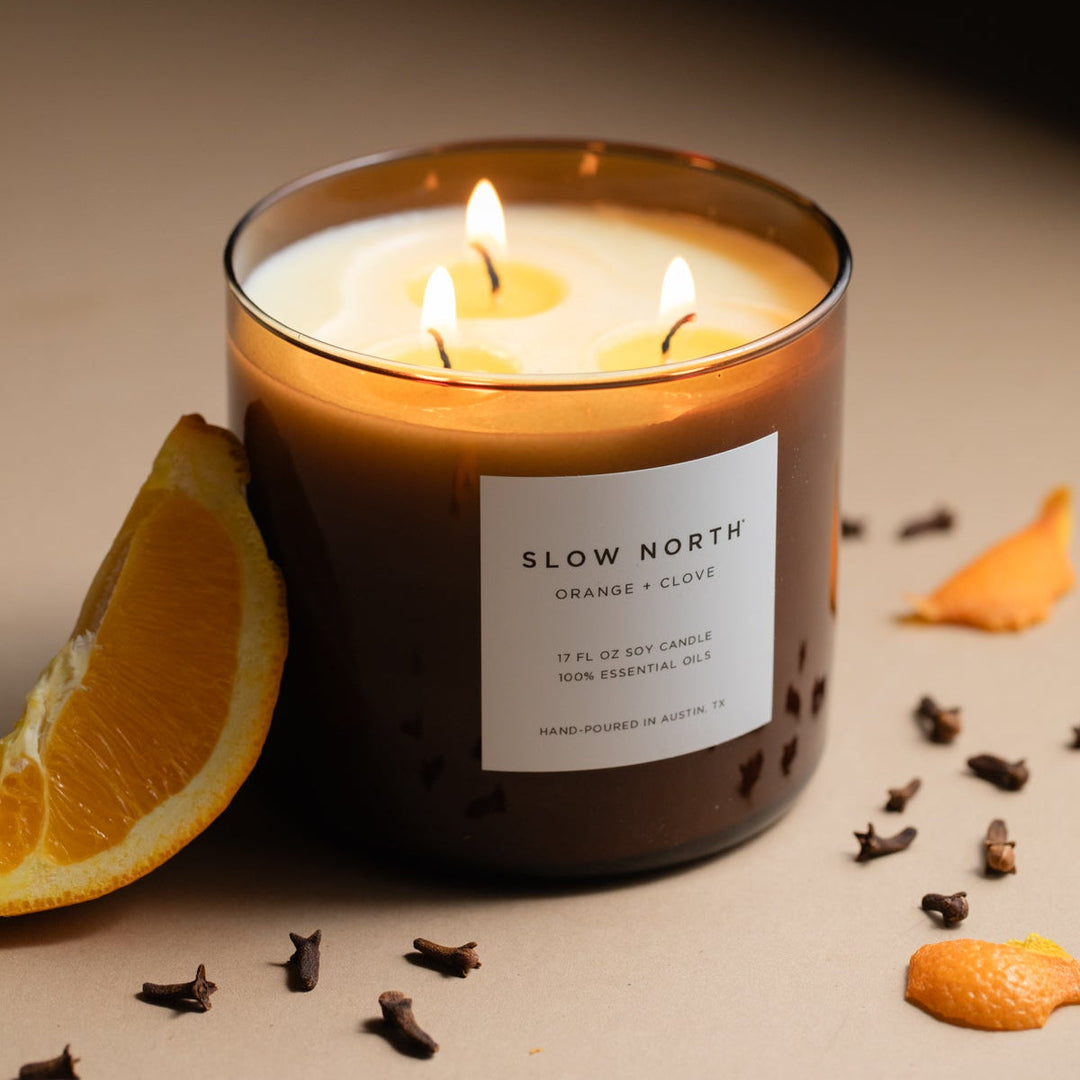 Orange Clove three-wick candle with orange and clove scent in a clear glass jar.