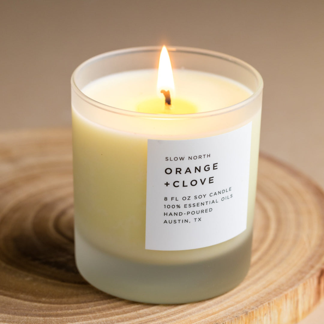 Signature candle with vibrant orange wax and flickering flame.