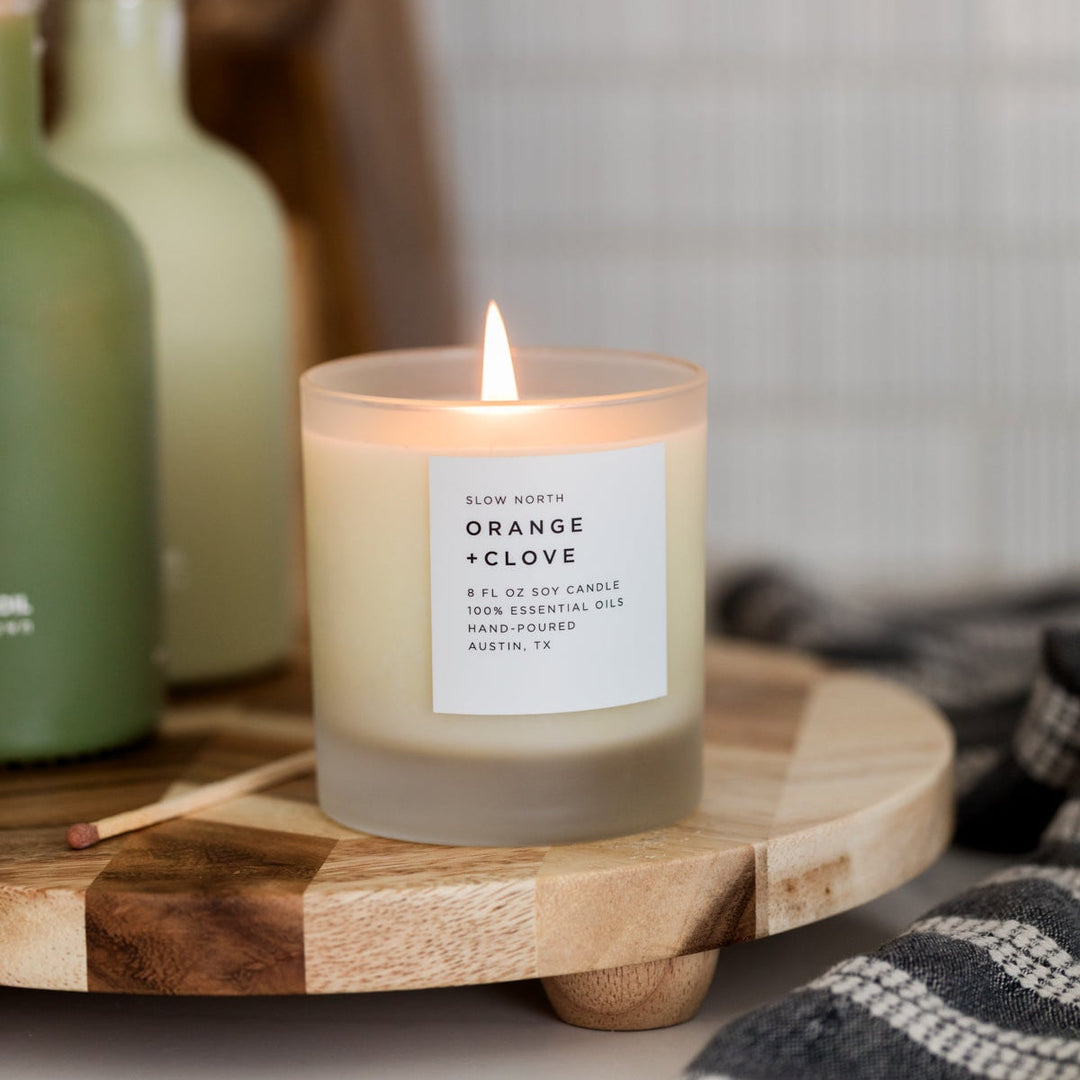 Orange clove candle with warm glow and essential oil blend.