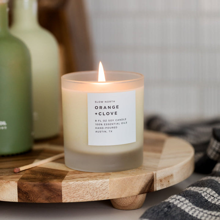 Orange clove candle with warm glow and essential oil blend.