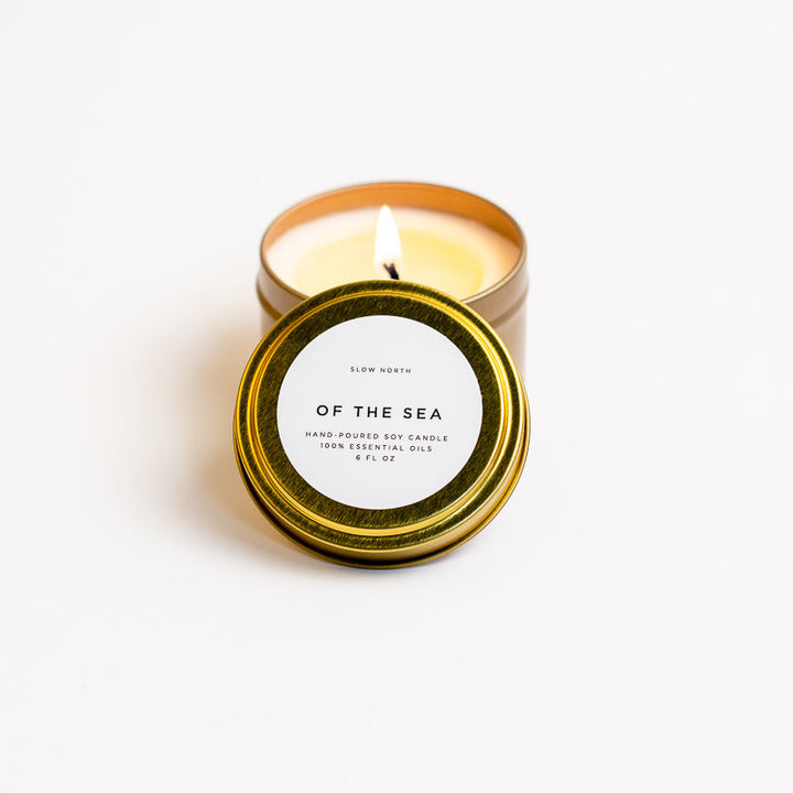 Of The Sea soy candle in a brushed gold travel tin with a soothing floral and herbal scent.