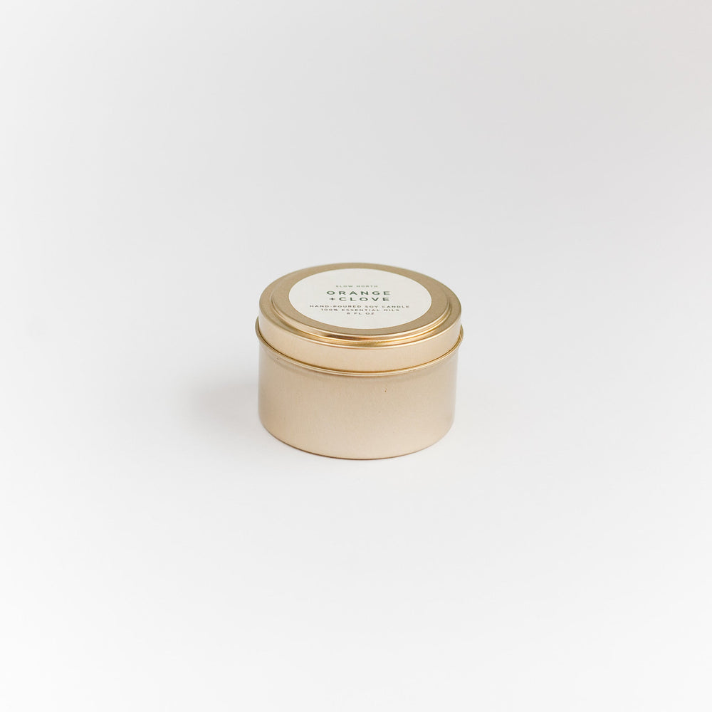 Orange clove soy candle in a compact brushed gold travel tin.