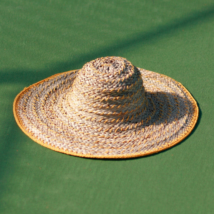 Wide round straw hat in butter yellow, featuring a woven design and wide brim for sun coverage.