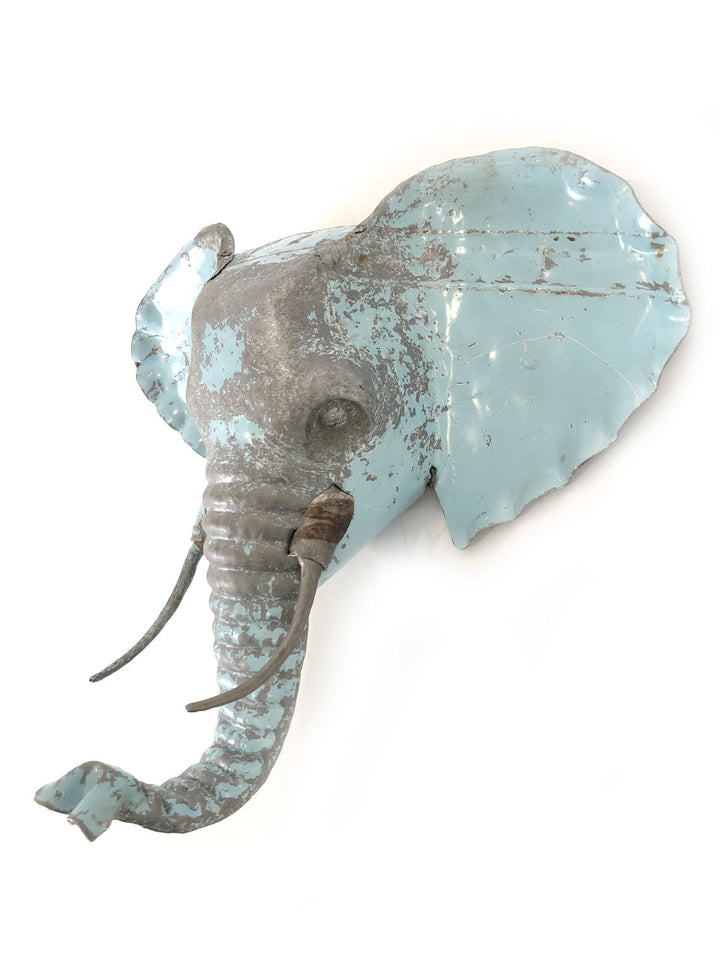 Three-dimensional recycled-metal elephant mask for artistic wall display.