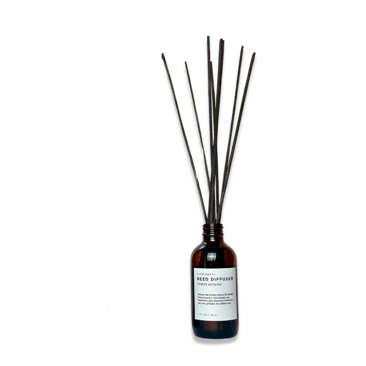 Forest Bathing reed diffuser with pine and patchouli scent in a clear glass bottle with rattan reeds.