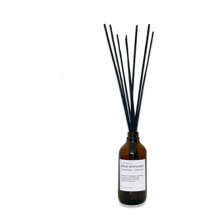 Lemongrass tangerine reed diffuser in a clear glass bottle with natural rattan reeds.