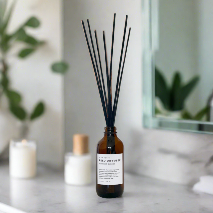Glass reed diffuser bottle with rattan reeds, styled with botanical accents.
