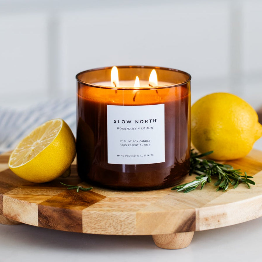 Rosemary Lemon three-wick candle in a glass jar with fresh lemon and rosemary sprigs.