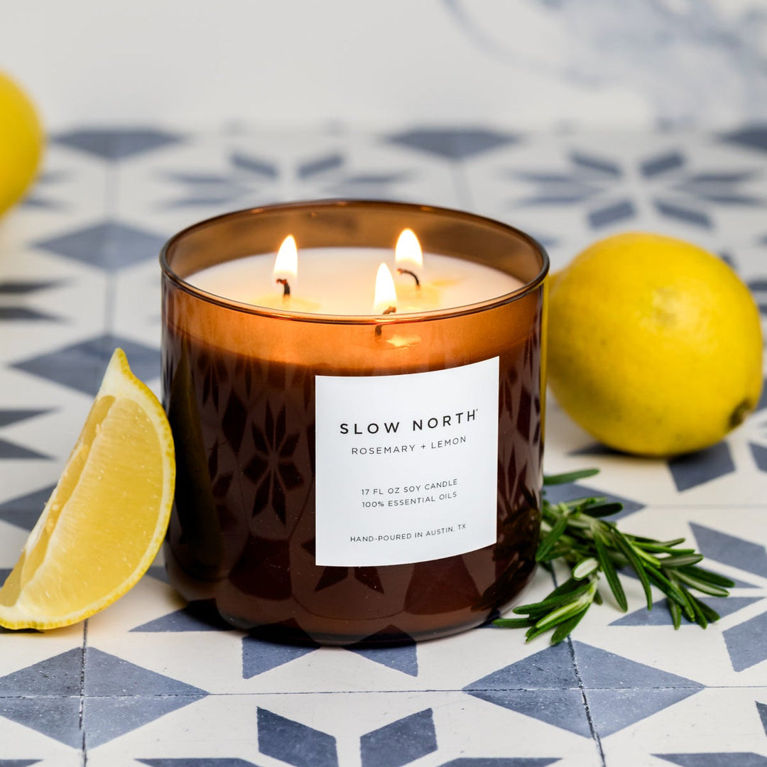 Rosemary Lemon three-wick candle in a glass jar with lit wicks.