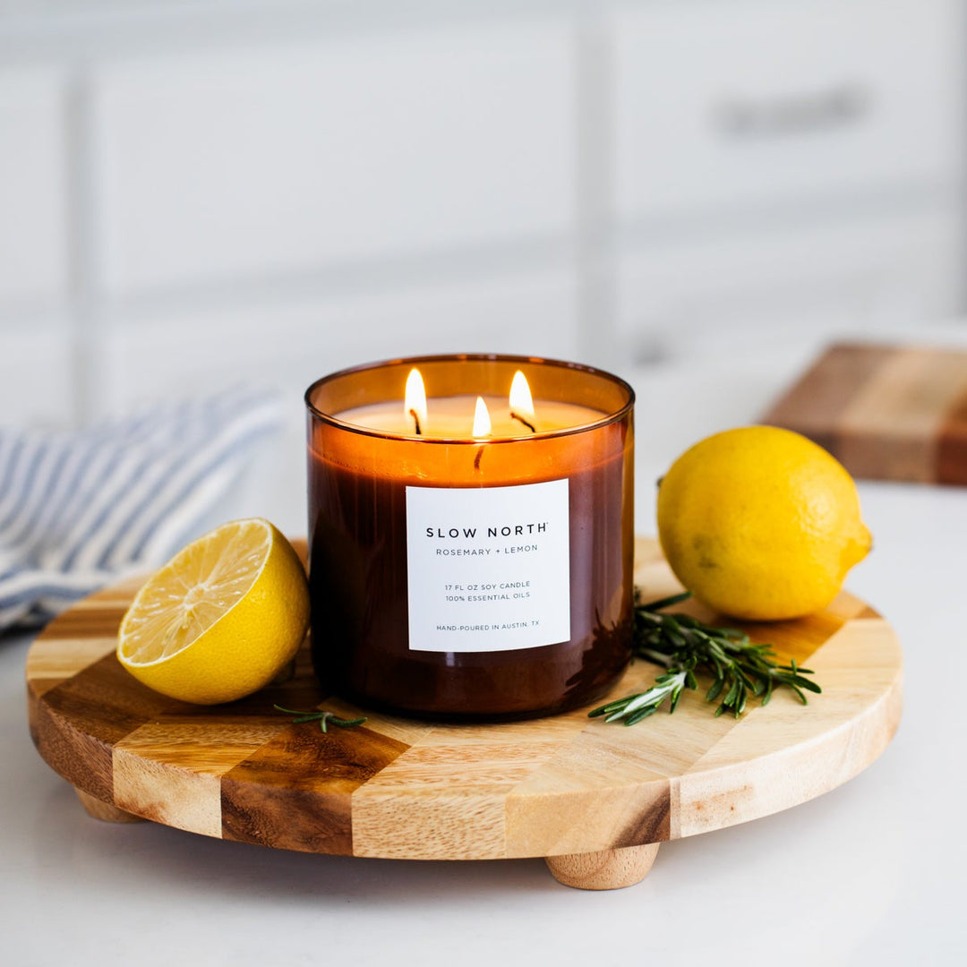 Rosemary Lemon three-wick candle in a glass jar with lit wicks for cozy ambiance.