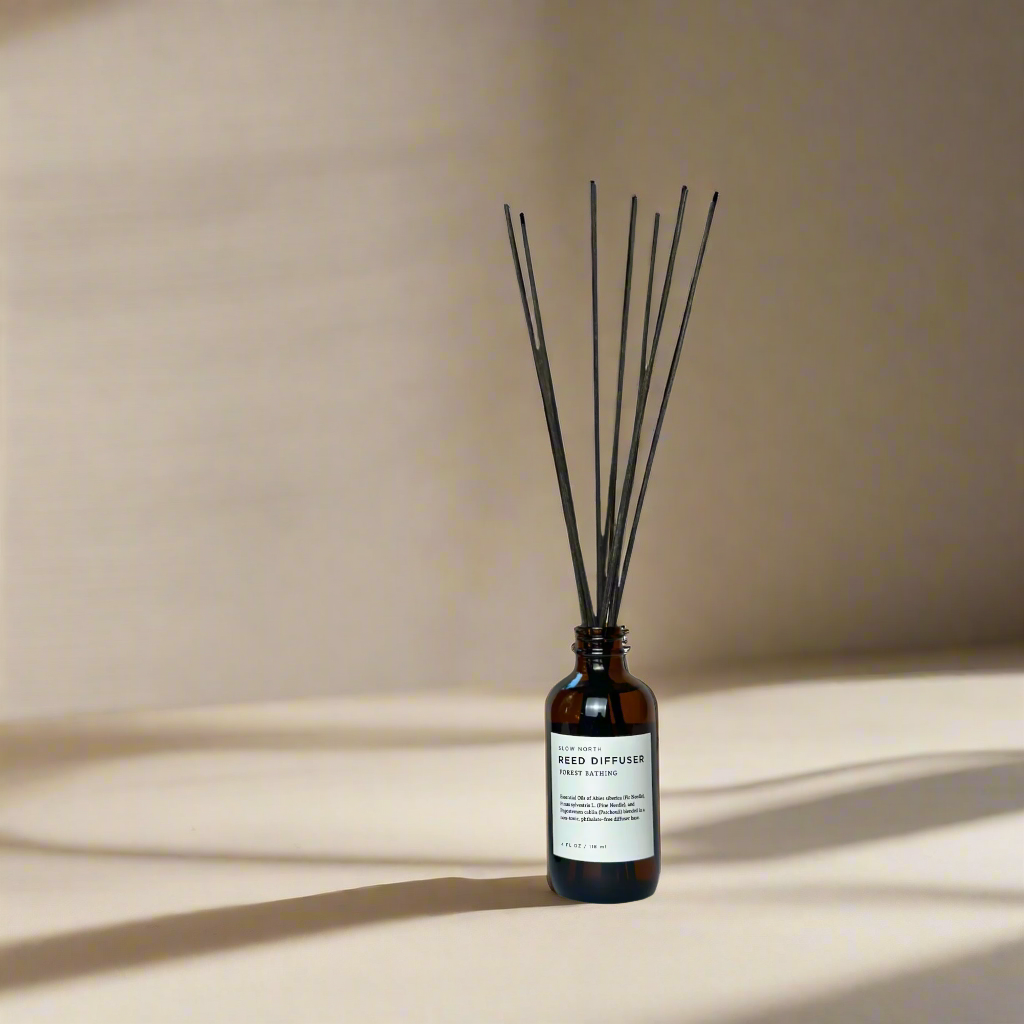 Pine and patchouli reed diffuser shown with reed sticks in a natural setting.