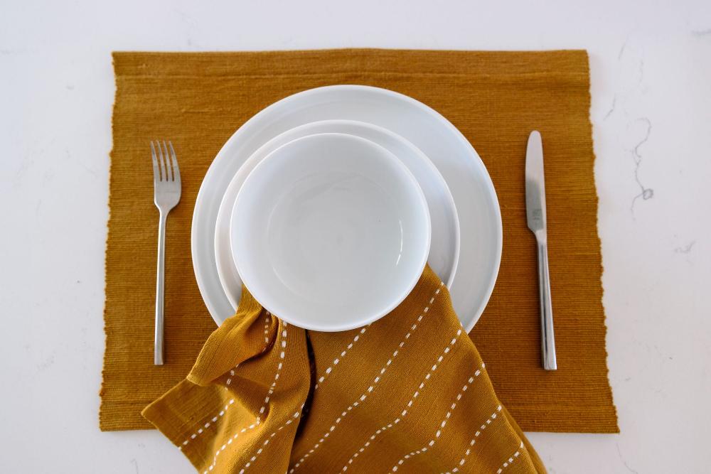 Bronze cocktail napkin on a placemat under a white plate and cutlery