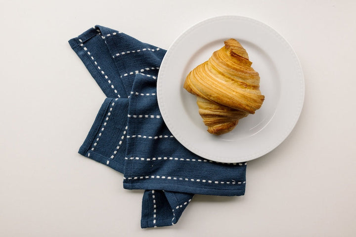 Navy cocktail napkin beside a plate of croissants