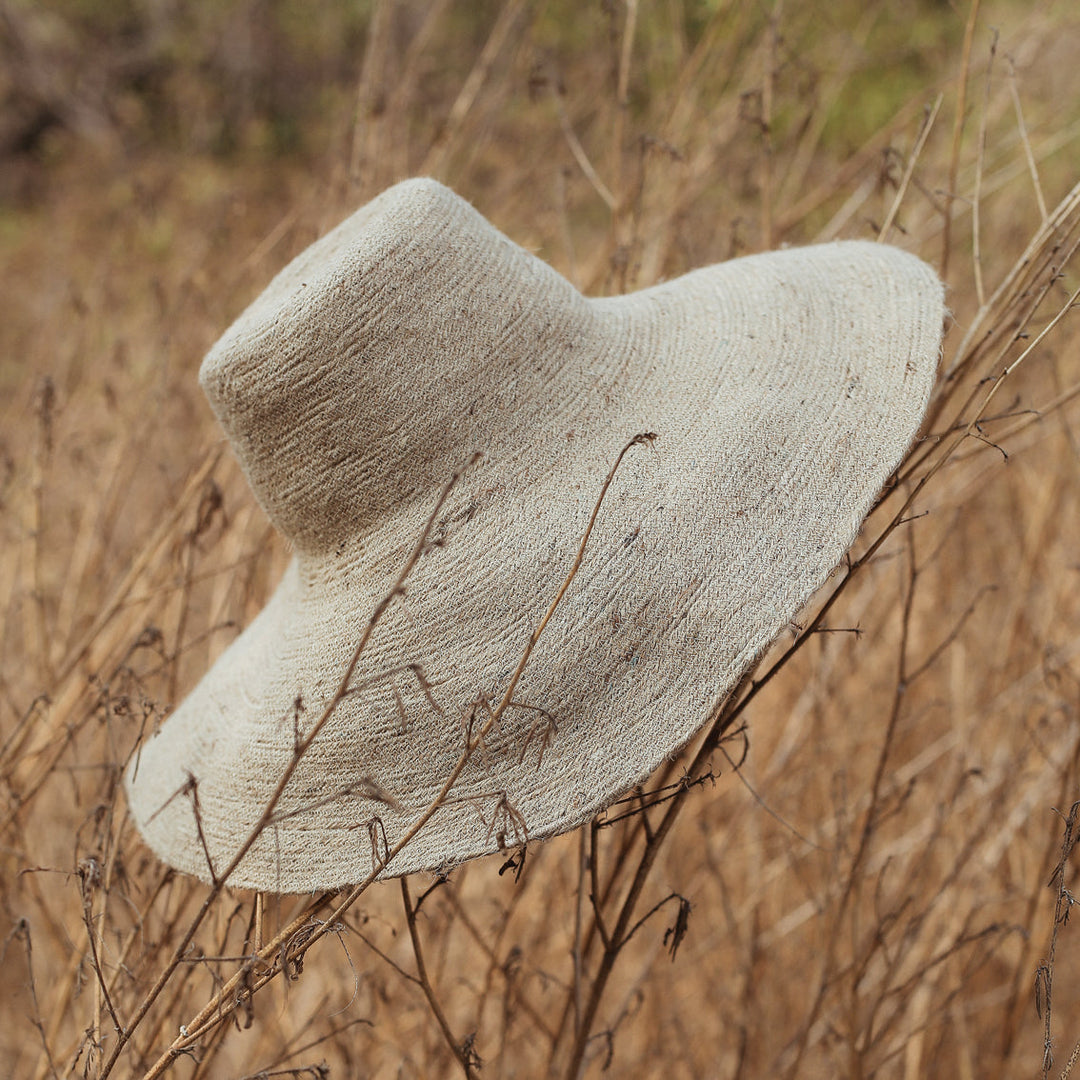 Handwoven jute hat in natural beige featuring a wide brim and stylish design for sun coverage and casual wear.