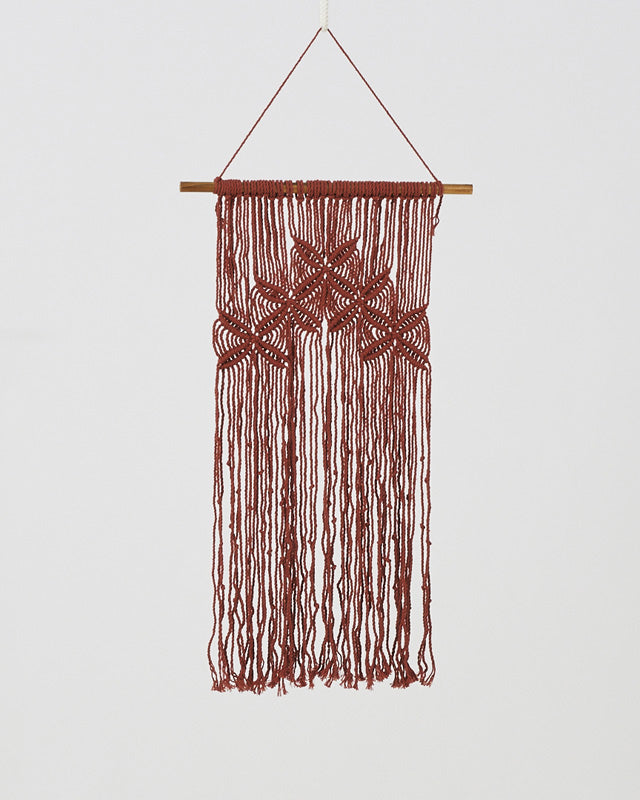 Tile-red macrame wall hanging with an intricate knotted pattern.