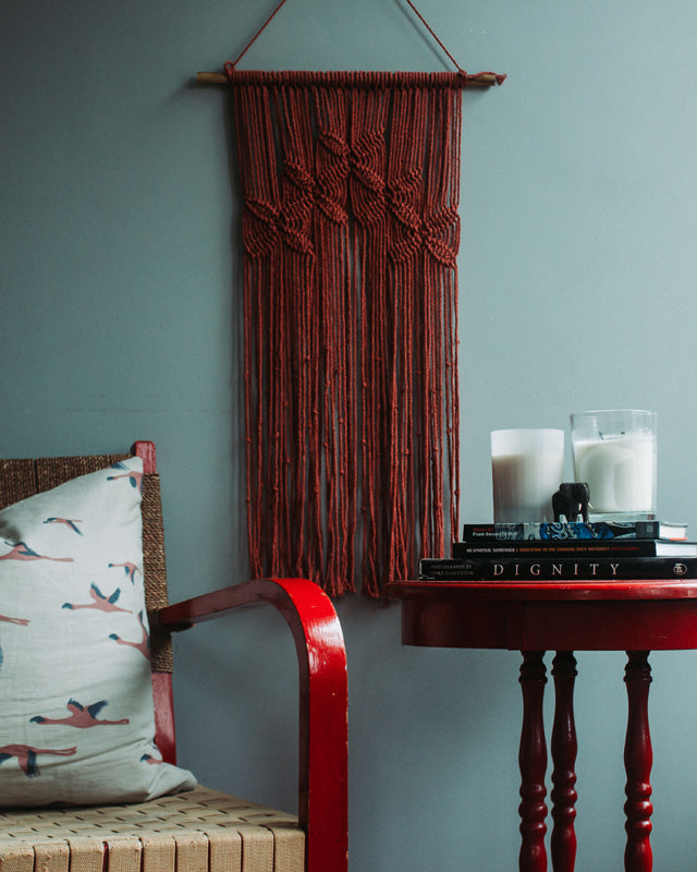 Tile-red macrame wall hanging with intricate knot detail.