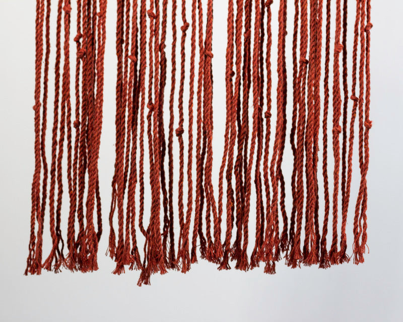 Tile-red macrame wall hanging with intricate knot patterns.