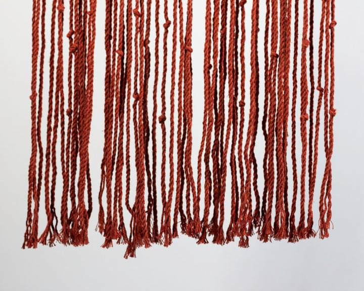 Tile-red macrame wall hanging with intricate knot patterns.