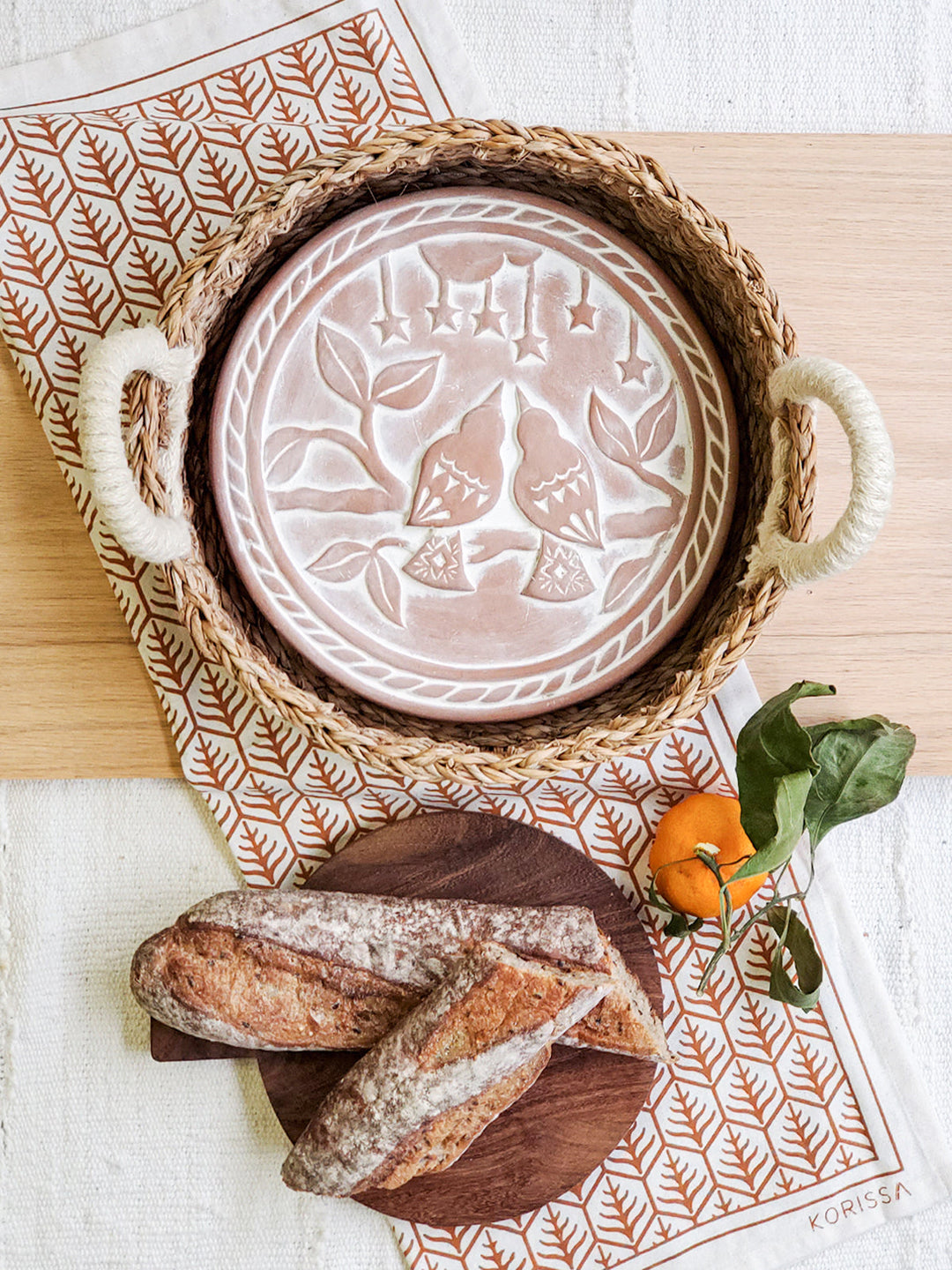 Round seagrass bread warmer basket with a lovebird-engraved terracotta plate