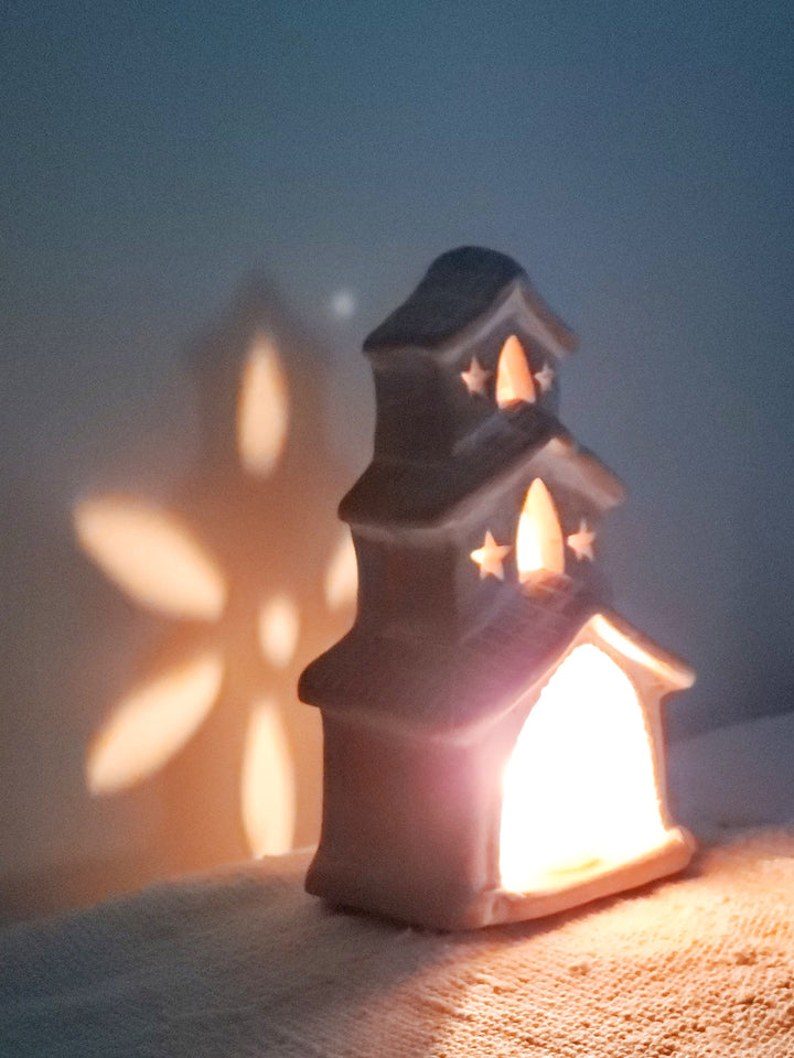 Terracotta house tea light lantern casting cutwork light patterns
