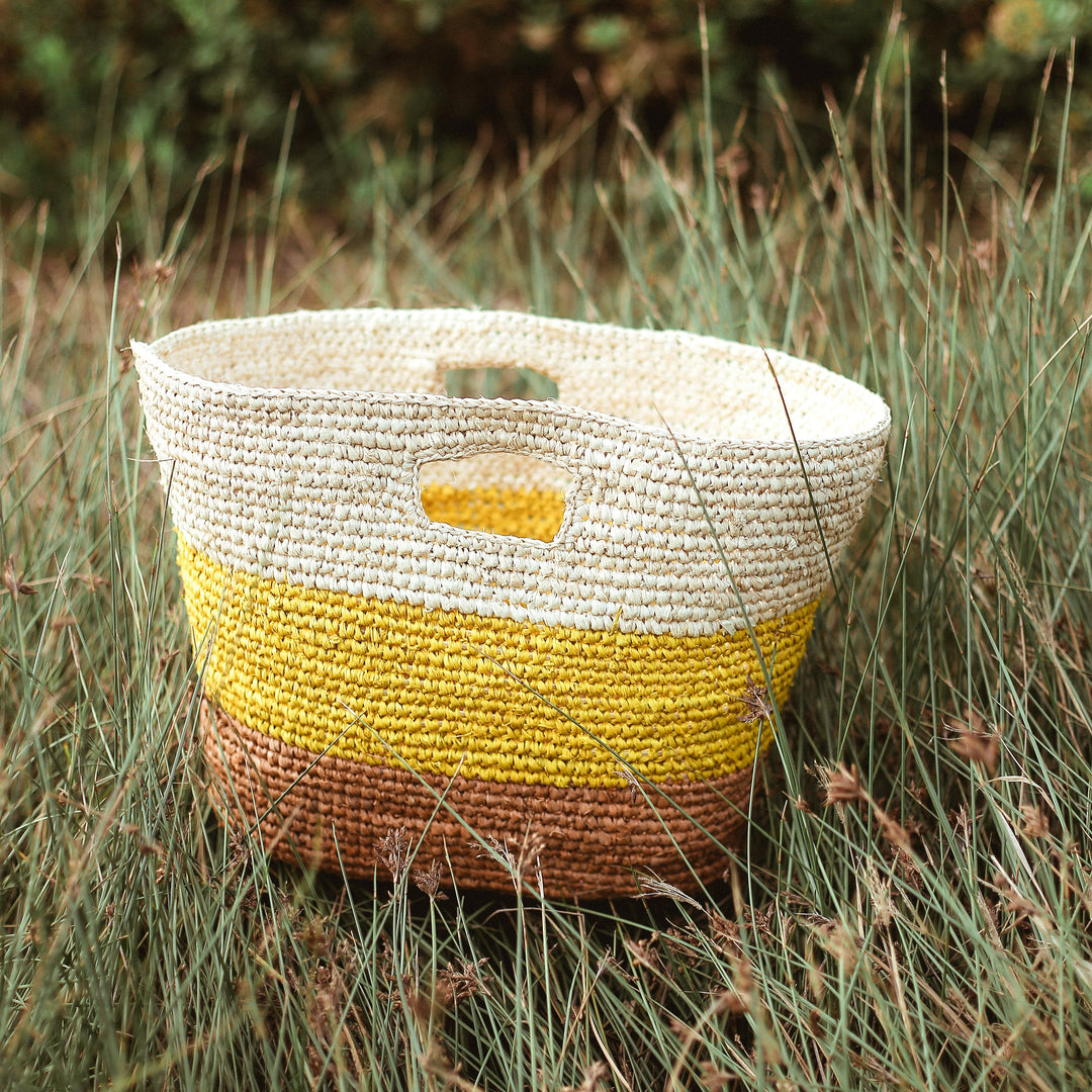 Yellow and beige raffia tote bag featuring a woven design and sturdy handles.