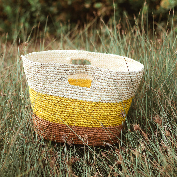 Yellow and beige raffia tote bag featuring a woven design and sturdy handles.