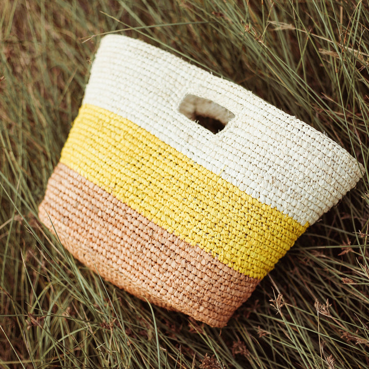 Yellow and beige raffia tote bag featuring natural woven texture and sturdy handles for casual carry.