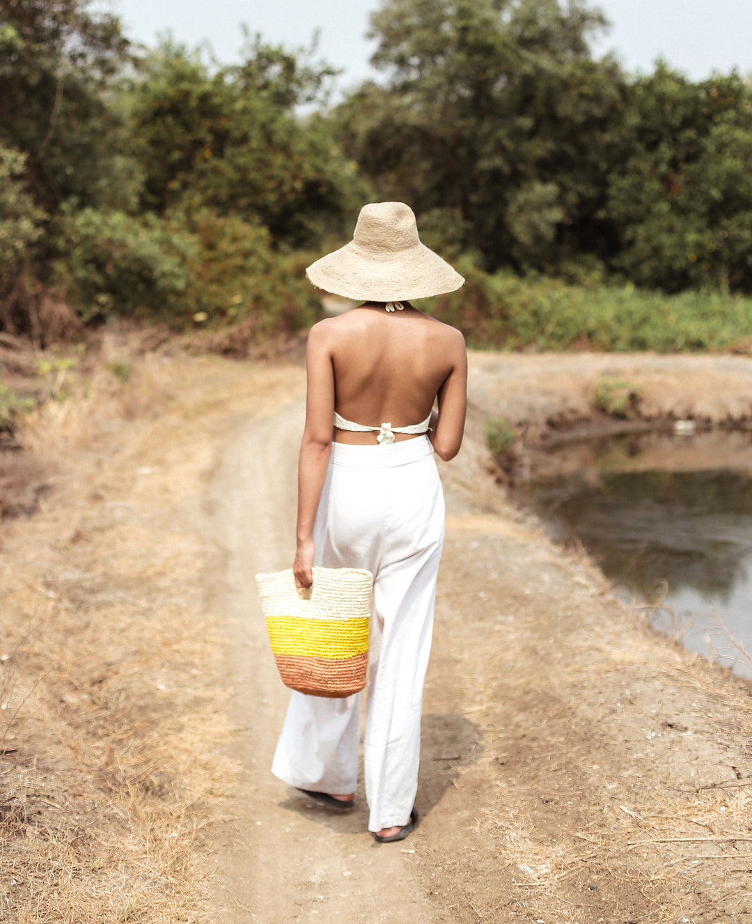 Yellow and beige raffia tote bag featuring a woven design and sturdy handles, perfect for casual outings.