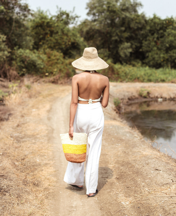 Yellow and beige raffia tote bag featuring a woven design and sturdy handles, perfect for casual outings.
