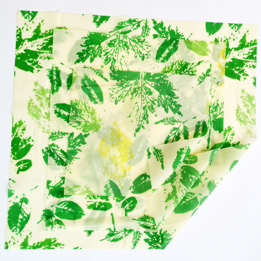 Set of three beeswax food wraps with colorful patterns on natural beeswax fabric.