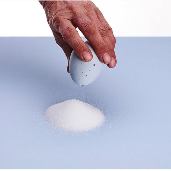 Egg-shaped porcelain salt shaker with a cork top, minimalist design.