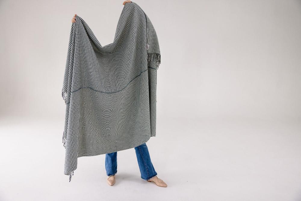 Person holding the slate pinwheel cotton throw open to show its full size.