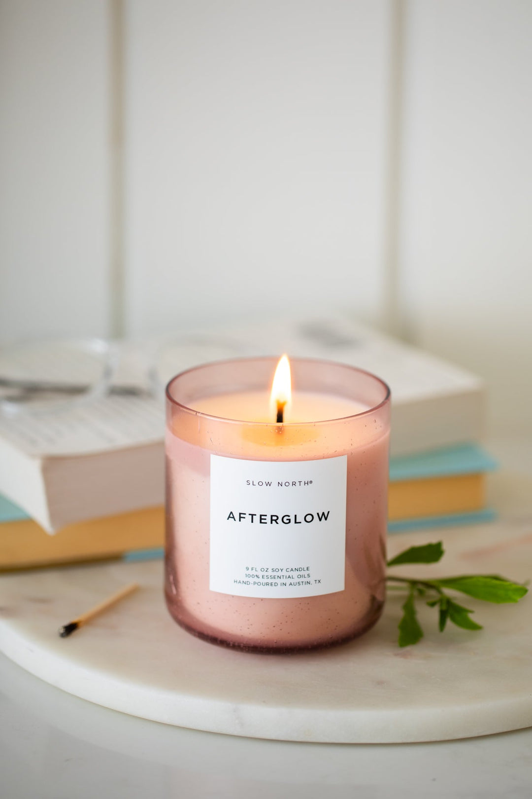 Afterglow Spa Collection candle with a lit wick in a blush pink bubble glass vessel.