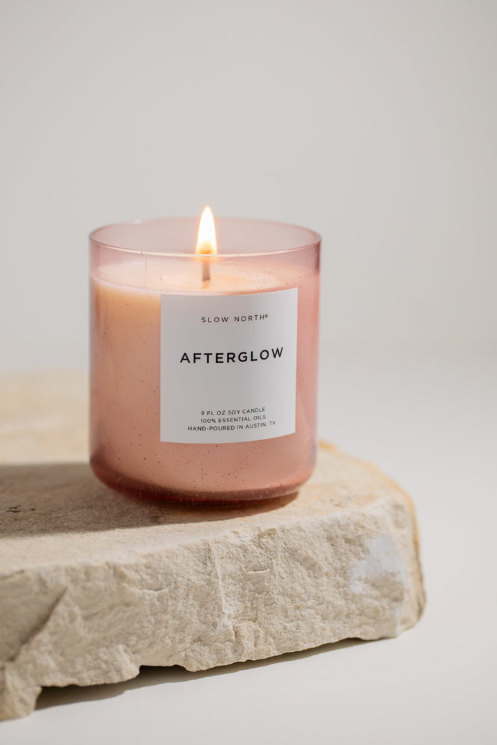 Afterglow Spa Collection candle burning with a soft glow in a blush pink bubble glass vessel.