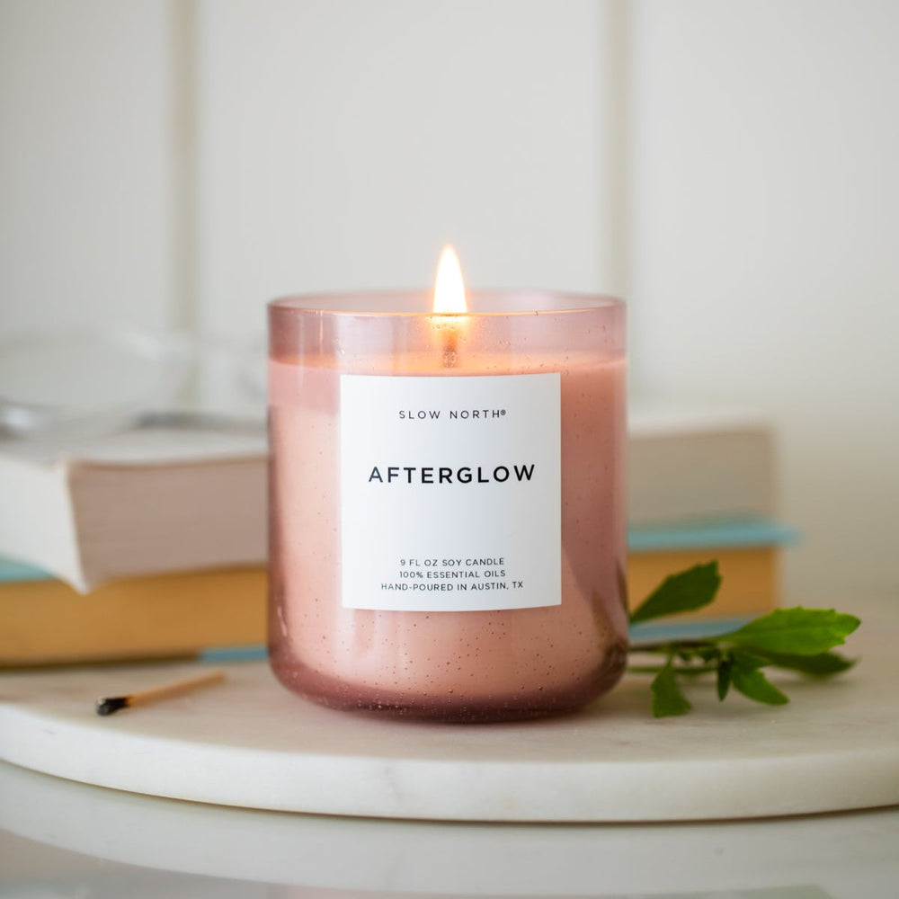 Afterglow Spa Collection candle in a blush pink bubble glass vessel with a soft flickering flame.