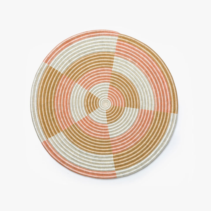 Large round blush flat woven wall hanging in sisal, shown overhead.
