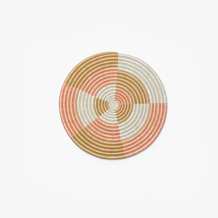 Small round blush flat woven wall hanging in sisal with a textured spiral weave.