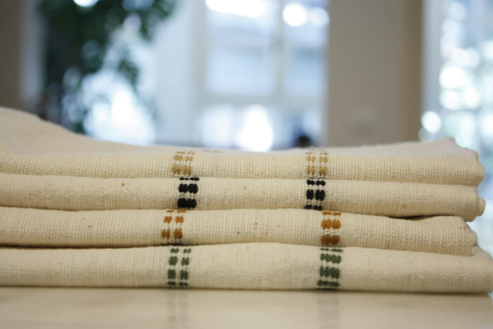 Stack of folded natural cotton napkins showing the woven check bands