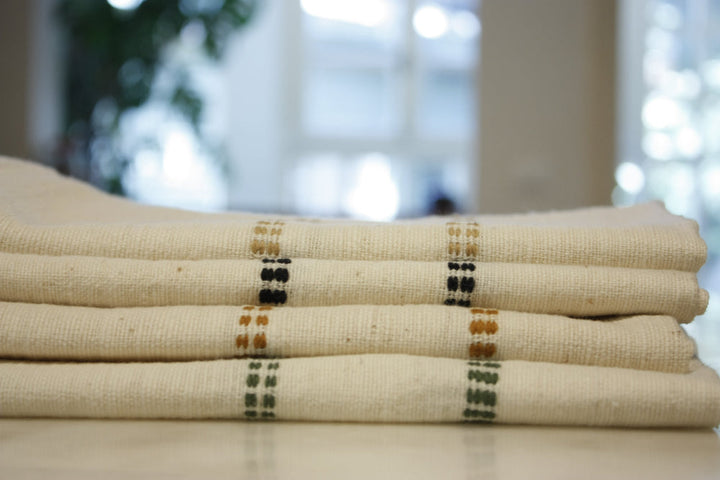 Stack of folded natural cotton napkins showing the woven check bands