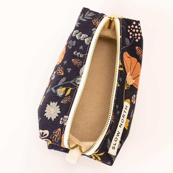 Travel pouch with earthy neutral tones and brass zipper closure.