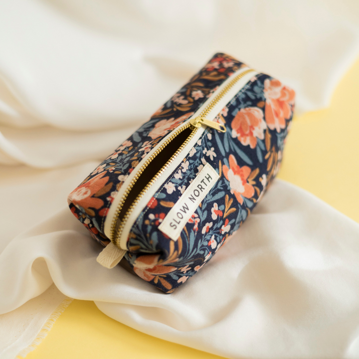 Pom Blossom travel pouch with pink and white pom accents and compact structured shape.